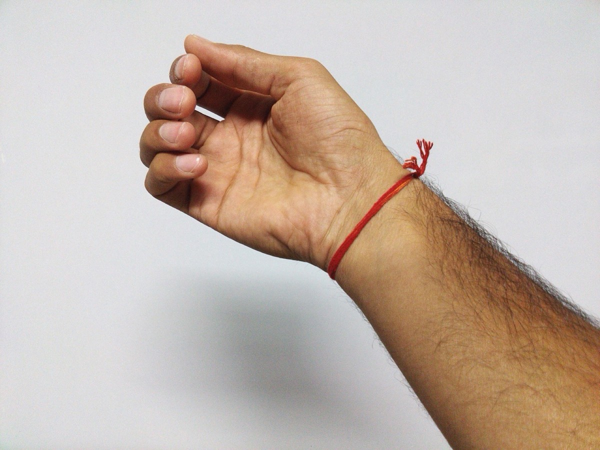 A red kalava thread tied around a wrist
